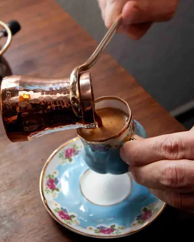 Café turc versé d'un cezve en cuivre dans une tasse